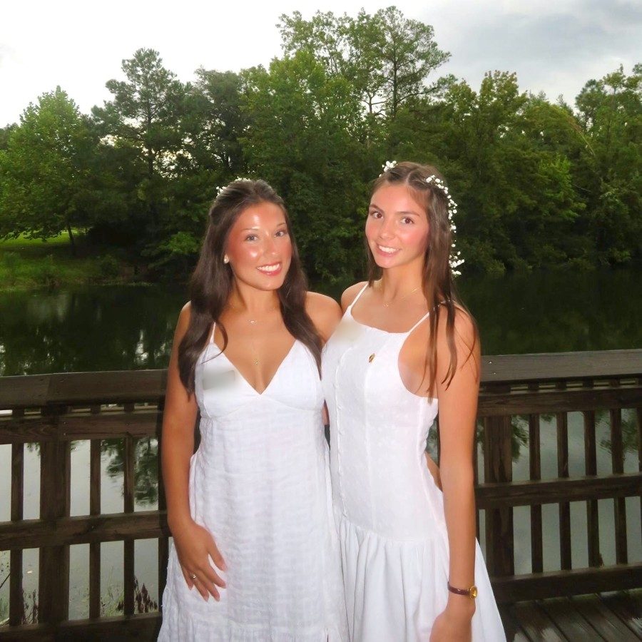 Two friends in white dresses by a lake