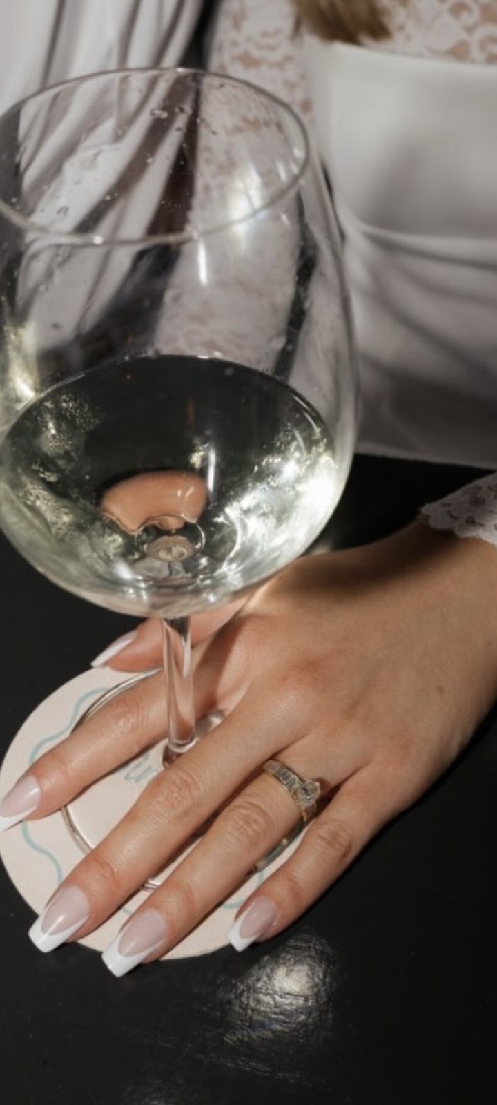 Hand with French manicure holding a glass of white wine
